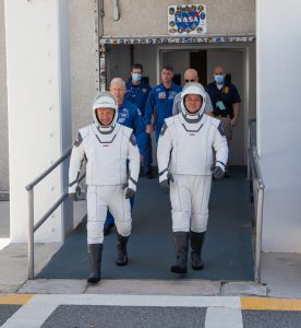On May 23, 2020, Demo-2 crew members Robert Behnken (right) and Douglas Hurley walk out of the Neil A. Armstrong Operations and Checkout Building as they prepare to be transported to historic Launch Complex 39A during a dress rehearsal ahead of NASA's SpaceX Demo-2 launch.