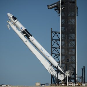 A SpaceX Falcon 9 rocket with the company's Crew Dragon spacecraft onboard is seen as it is raised into a vertical position on the launch pad at Launch Complex 39A.