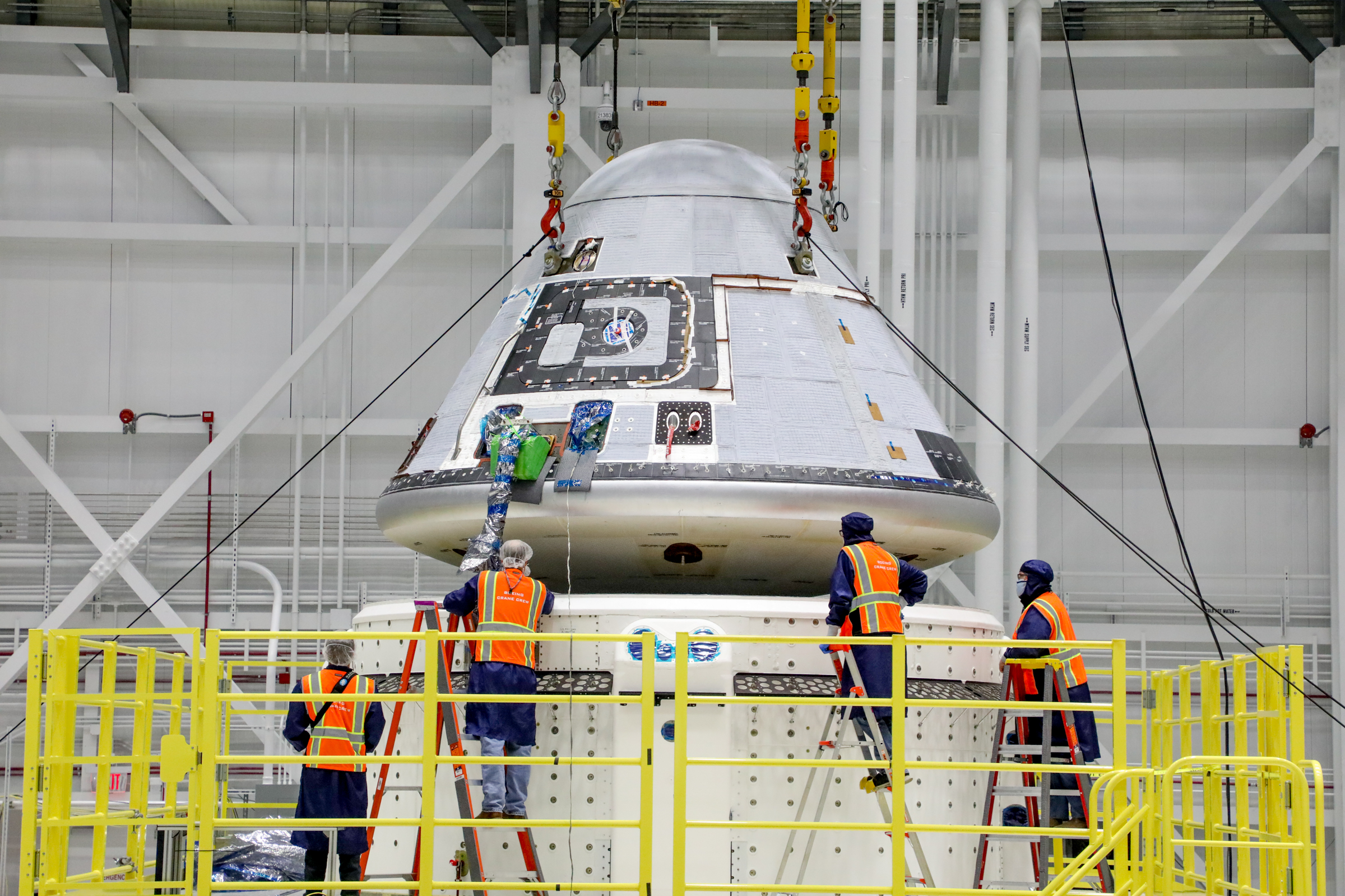 Technicians observe Boeing's Starliner crew module being placed on top of the service module in the Commercial Crew and Cargo Processing Facility at NASA's Kennedy Space Center in Florida on Jan. 14, 2021.