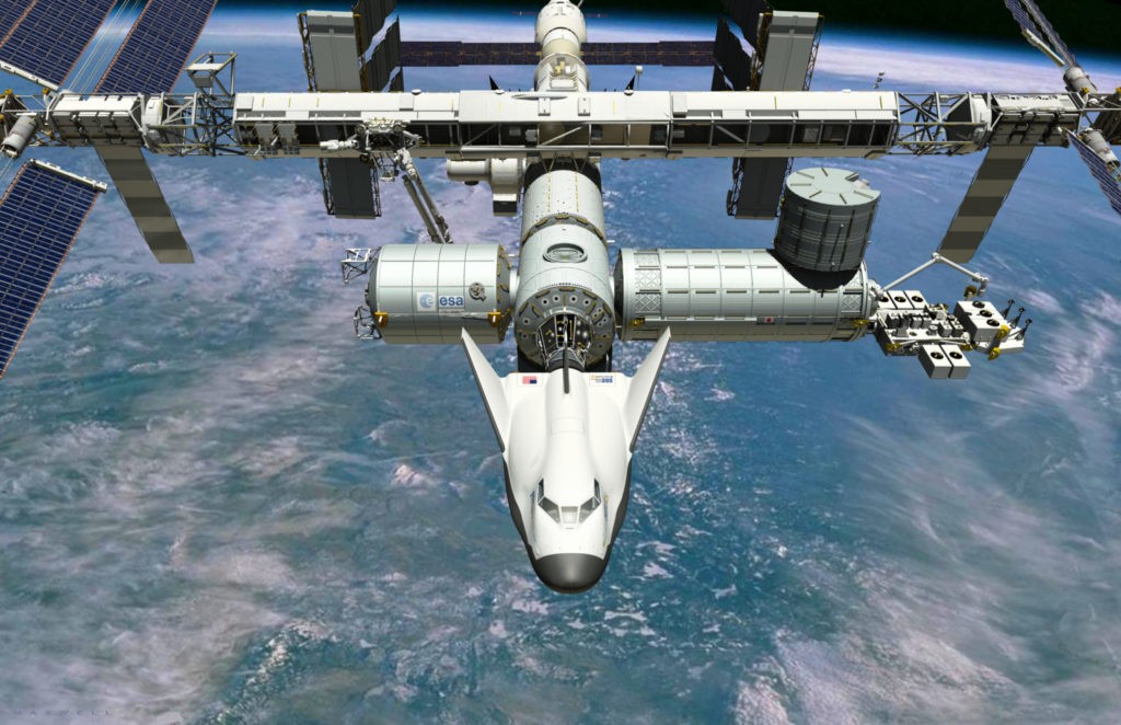 Крылатый многоразовый космический корабль Dream Chaser, пристыкованный к МКС, в представлении художника. Sierra Nevada Space Systems