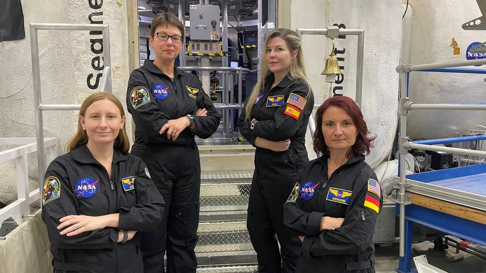 The crew for the next mission of NASA's Human Exploration Research Analog, or HERA, stand outside the HERA habitat  Pictured from left to right: Katie Koube, Kimberly Knish, Vanesa Gomez Gonzales, and Sandra Herrmann.