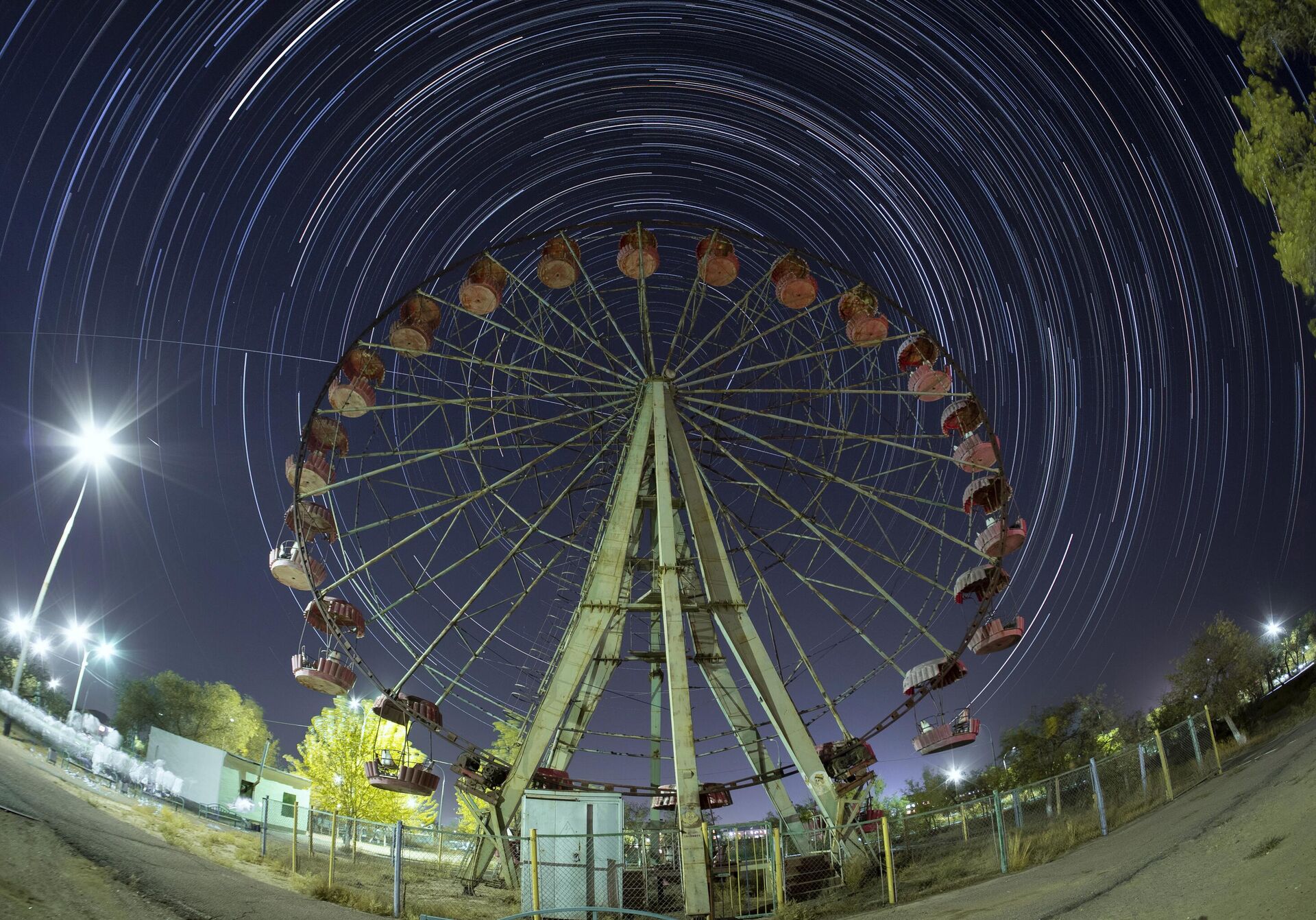 Международная космическая станция (МКС) движется по прямой линии по небу слева направо по своей орбите над колесом обозрения на космодроме Байконур - Sputnik Казахстан, 1920, 25.06.2025